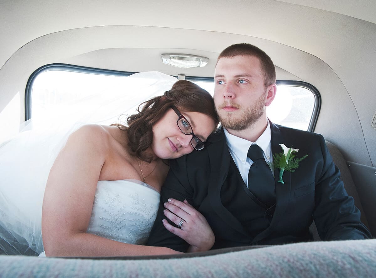 wedding couple take photos in the back of a vintage car on their wedding day