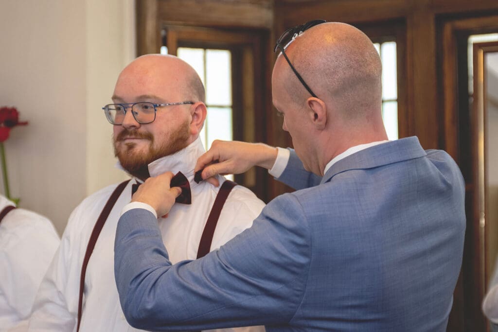 groomsman getting help with bowtie