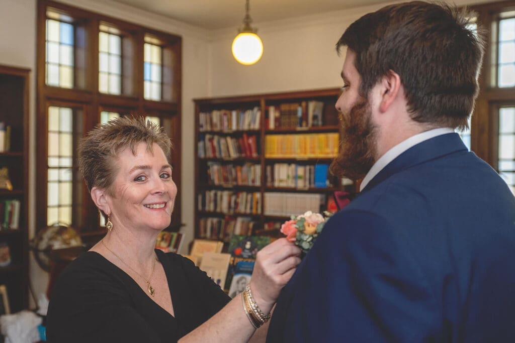 mother of groom puts on his boutonniere