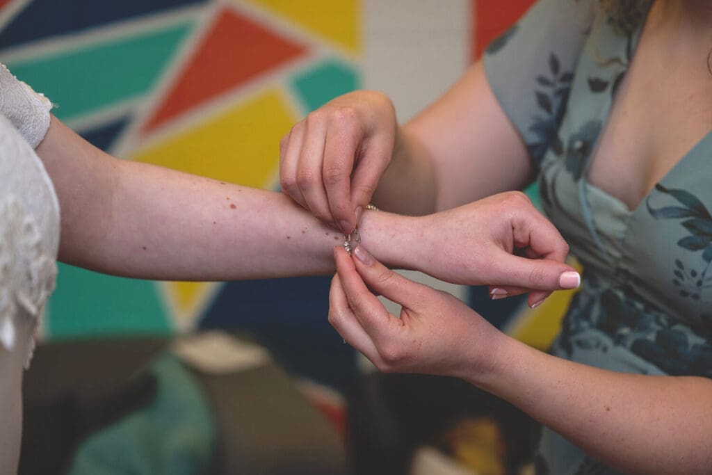 maid of honor puts bracelet on bride