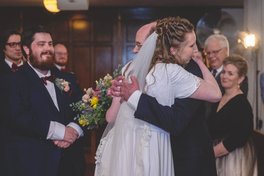 father of the bride hugs bride at the alter