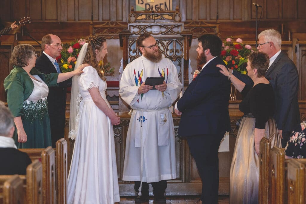 parents pray over bride and groom