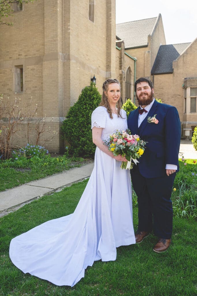 bride and groom pose in front of church