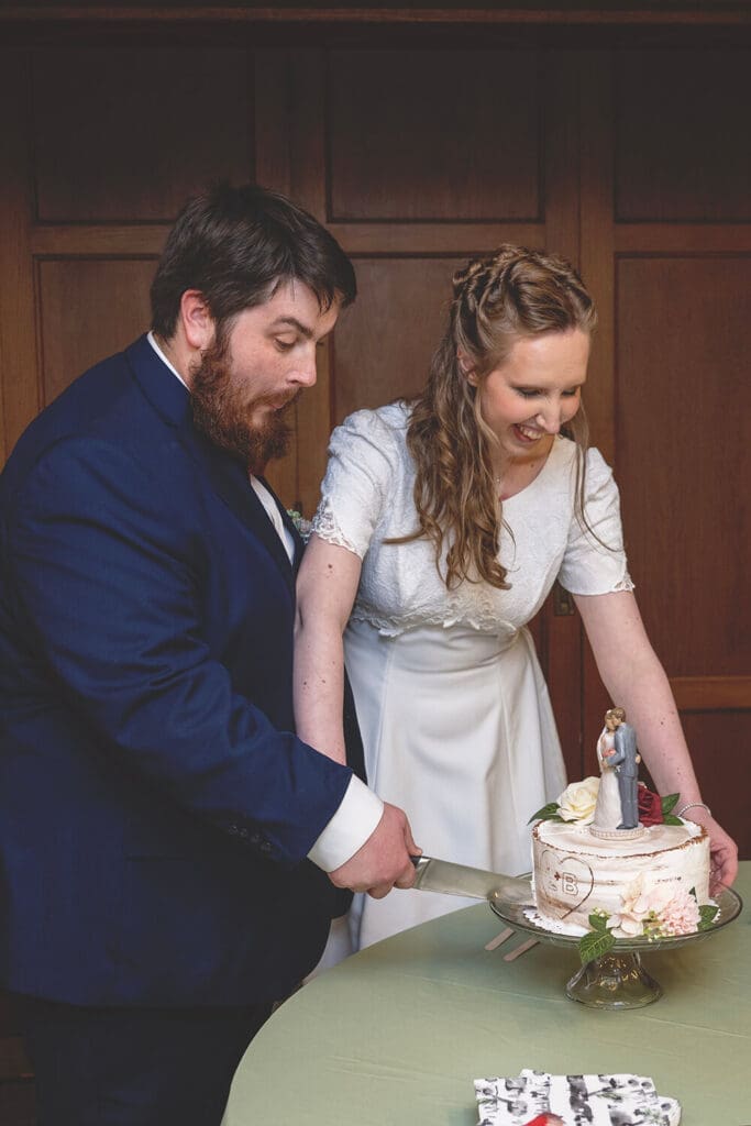 bride and groom cut wedding cake that tips