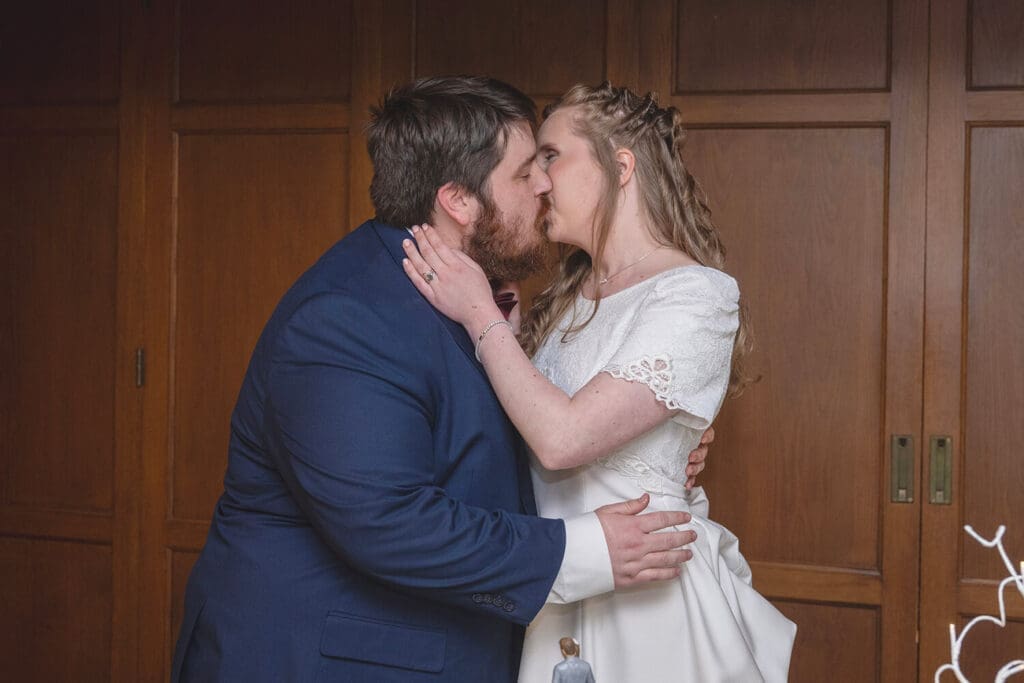 bride and groom kiss after sharing cake