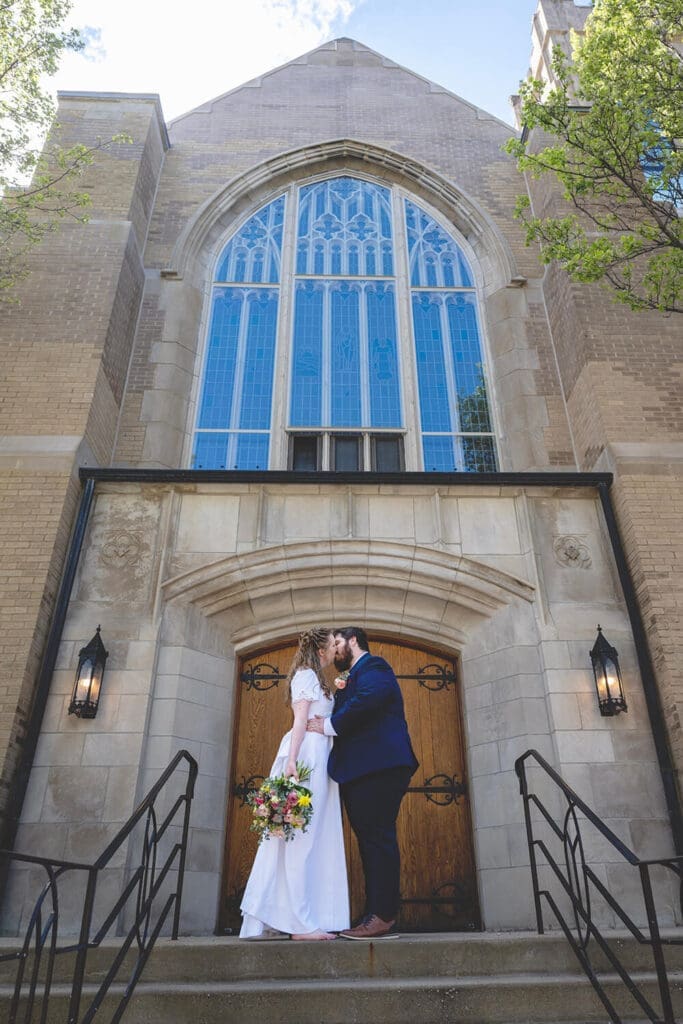 bride and groom kiss in front of church