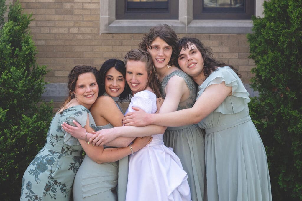 bride and bridesmaids hug during wedding portraits