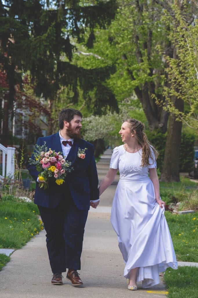 bride and groom walk down sidewalk
