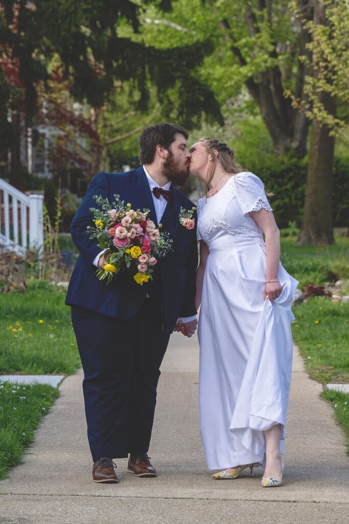 bride and groom kiss on sidewalk