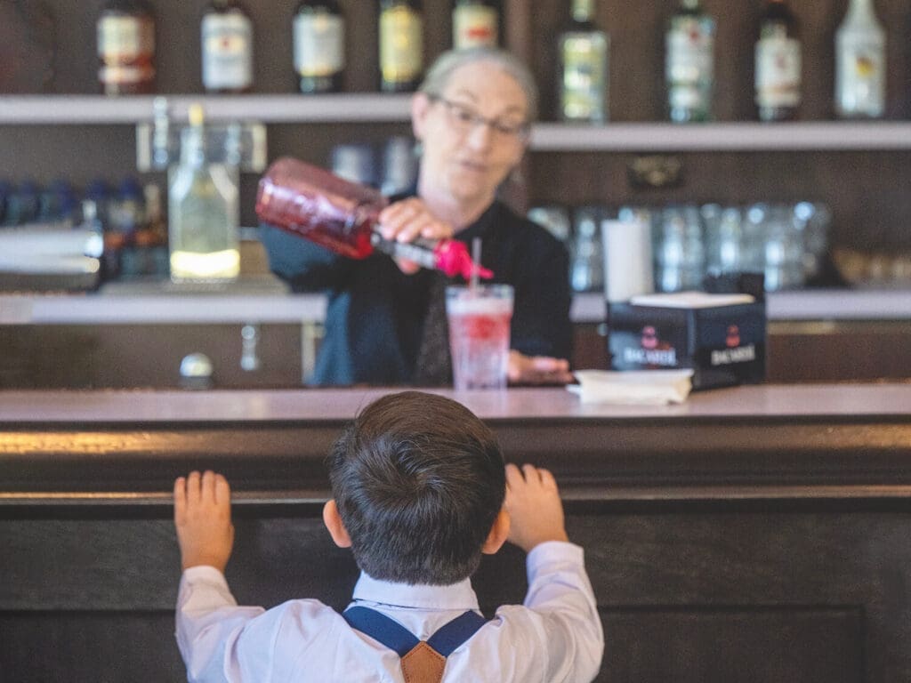 Little boy waits for a fun drink at a wedding reception