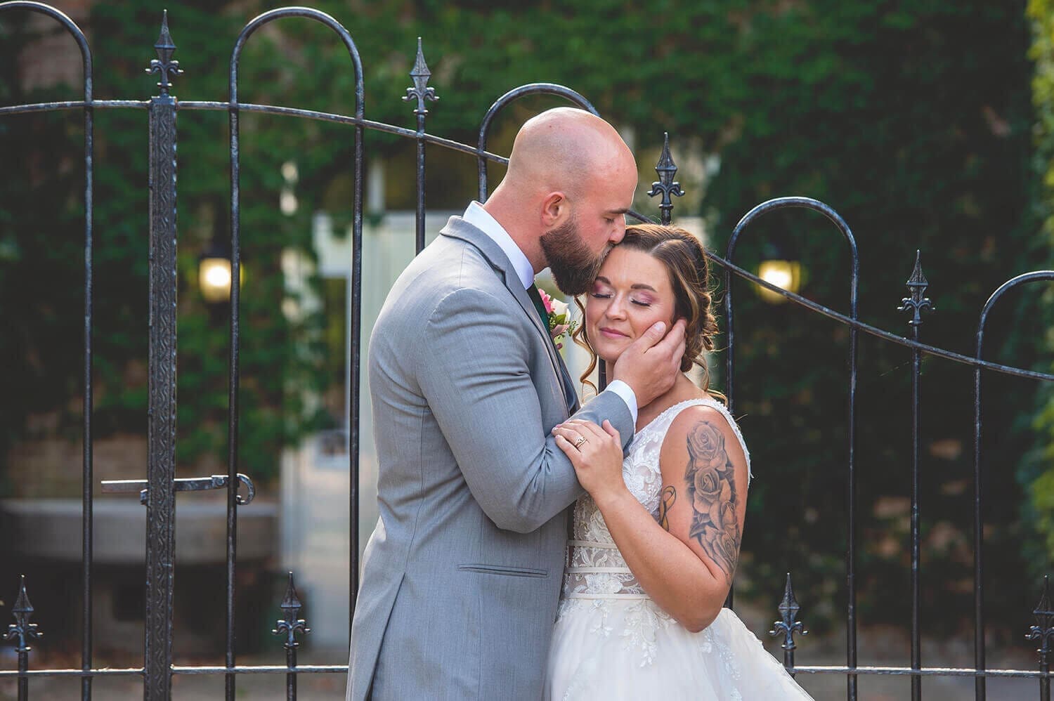 Wedding couple embrace in front of gate at Starline Factory in Harvard, IL