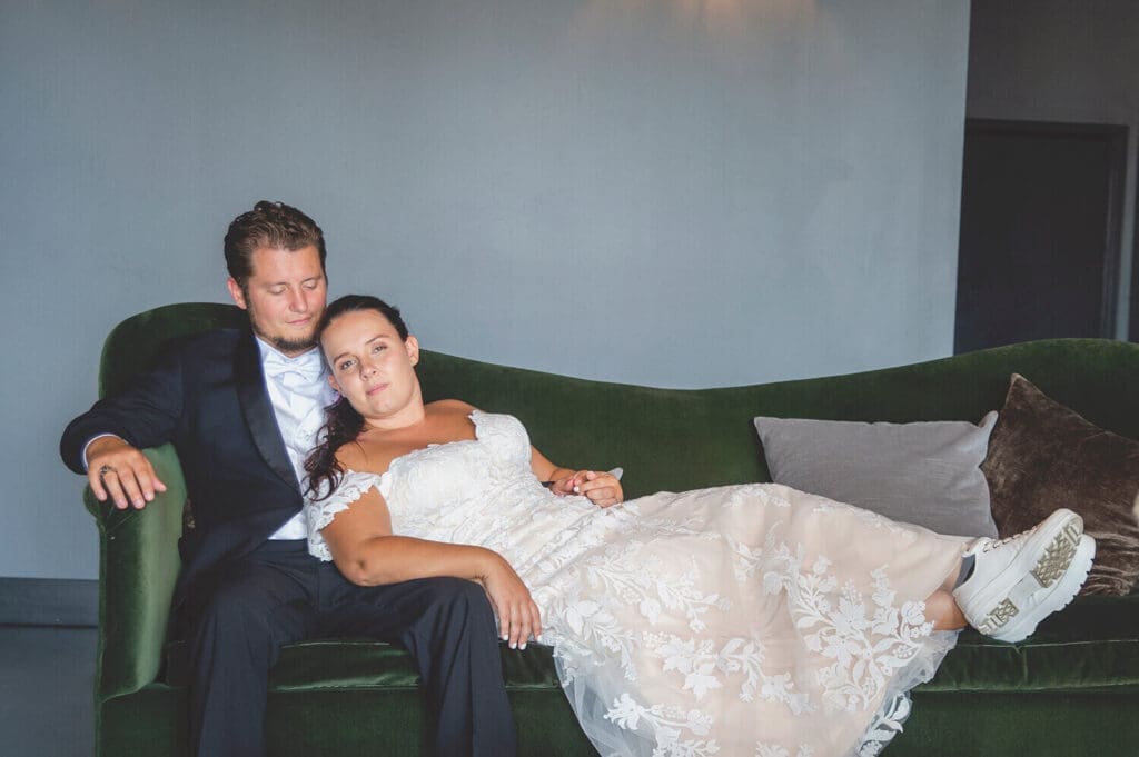 Bride and groom lounge on coach at The Standard in Rockford, IL